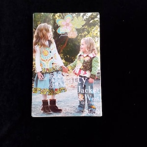 May include: A quilting pattern booklet featuring two girls wearing a quilted jacket and vest. The cover features a floral design and the text "the girly jacket & vest quilted no. 9".