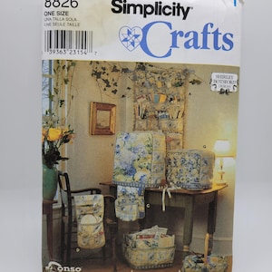May include: Simplicity Crafts sewing pattern featuring various home decor items. The pattern includes instructions for making items like chair covers, storage baskets, and table covers. The items have a floral pattern with blue and yellow accents.