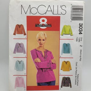 May include: McCall's sewing pattern envelope featuring a woman in a pink top with floral embroidery. The envelope displays various top designs in different colors, with the text "GREAT LOOKS 1 EASY PATTERN".
