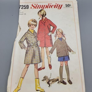 May include: Vintage Simplicity sewing pattern featuring illustrations of three girls in coats, with a dachshund dog. The pattern cover includes the text "7259 Simplicity" and "Girl Size 8 Breast 26".