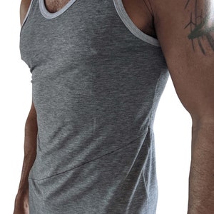 May include: A gray sleeveless shirt with a white trim around the neckline. The shirt is made of a soft, comfortable fabric and has a relaxed fit.