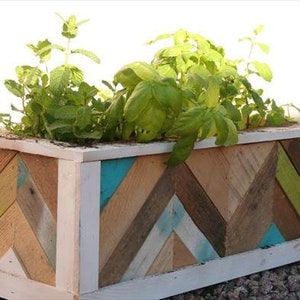 May include: A wooden planter box with a chevron pattern made from reclaimed wood painted in shades of brown, green, blue, and white.