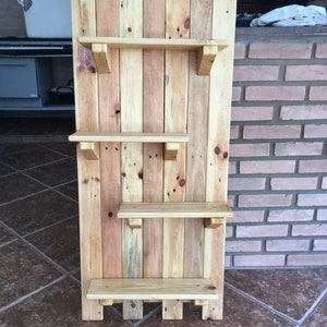May include: A wooden shelf unit made from reclaimed pallet wood. The shelf has four shelves and is stained in a light brown color.