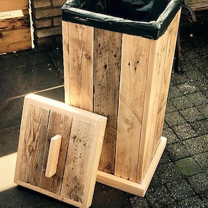 May include: A wooden trash can with a lid and a black plastic liner. The trash can is made from reclaimed wood and has a rustic look.