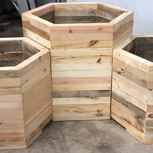 May include: Three hexagonal wooden planters made from reclaimed wood. The planters are different sizes and are arranged in a staggered formation.