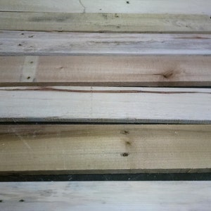 May include: A close-up of a stack of wooden planks. The planks are various shades of brown and beige, with some showing signs of wear and tear.