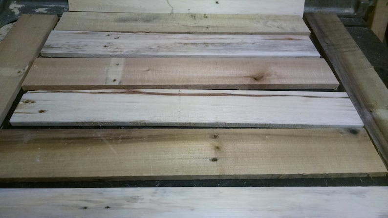 May include: A close-up of a stack of wooden planks. The planks are various shades of brown and beige, with some showing signs of wear and tear.