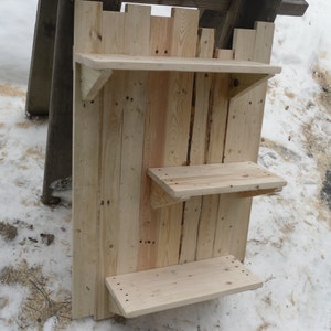 May include: A rustic wooden shelf unit with three shelves. The shelves are made from reclaimed wood and have a natural finish. The unit is mounted on a wall and is perfect for displaying small items.