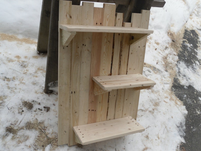 May include: A rustic wooden shelf unit with three shelves. The shelves are made from reclaimed wood and have a natural finish. The unit is mounted on a wall and is perfect for displaying small items.