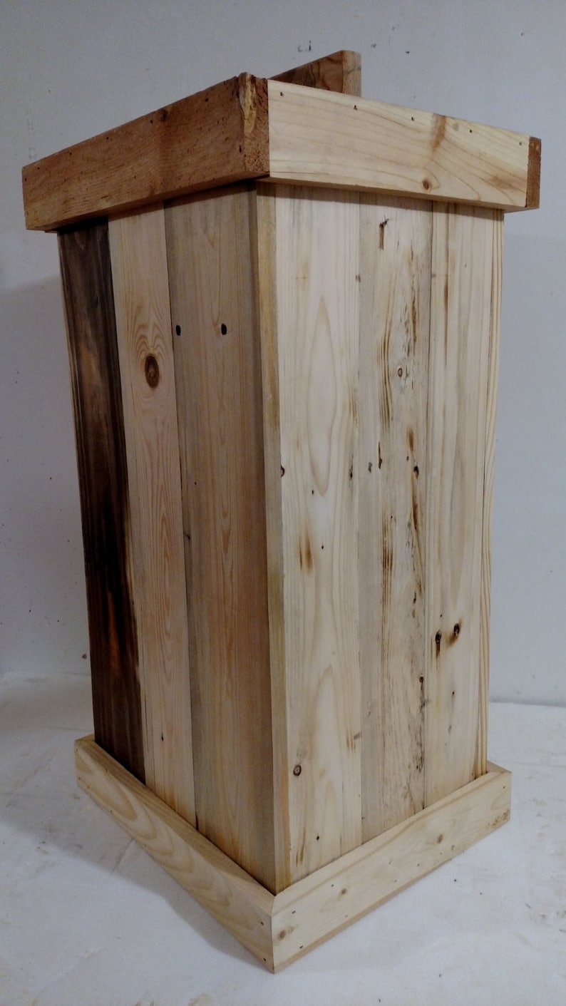 May include: A wooden box with a natural wood finish. The box is made of reclaimed wood and has a rustic look. The box is square and has a simple design.