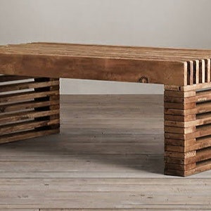 May include: A wooden coffee table with a unique slatted design on the legs. The table top is made of solid wood and has a natural finish.