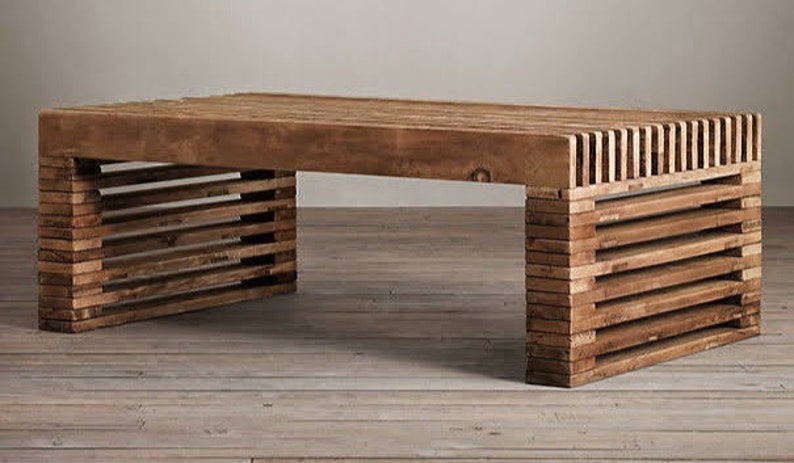 May include: A wooden coffee table with a unique slatted design on the legs. The table top is made of solid wood and has a natural finish.