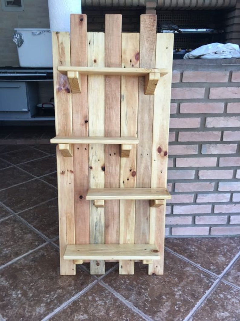 May include: A wooden shelf unit made from reclaimed pallet wood. The shelf has four shelves and is stained in a light brown color.