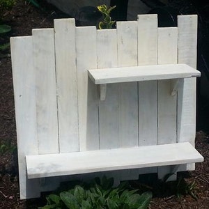 May include: White painted wooden shelf unit with two shelves. The shelves are made from reclaimed wood planks.