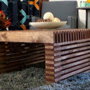 May include: A wooden coffee table with a dark brown base and a lighter brown top. The base has a slatted design and the top is a solid piece of wood.