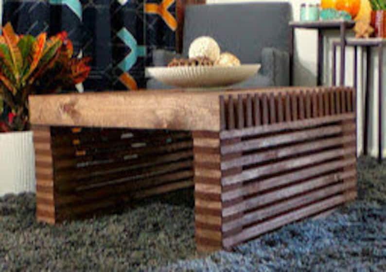 May include: A wooden coffee table with a dark brown base and a lighter brown top. The base has a slatted design and the top is a solid piece of wood.