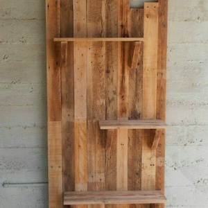 May include: A rustic wooden shelf unit made from reclaimed pallet wood. The shelf has three shelves and is mounted on a wall.