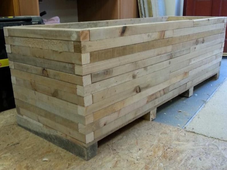 Op de afbeelding: Een grote houten plantenbak gemaakt van gerecycled hout. De bak is gemaakt van natuurlijk hout met een rustieke uitstraling.