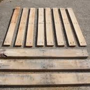 May include: Ten wooden planks, some with nail holes, arranged in two rows. The planks are all approximately the same length and width. They are a light brown color and appear to be made of reclaimed wood.