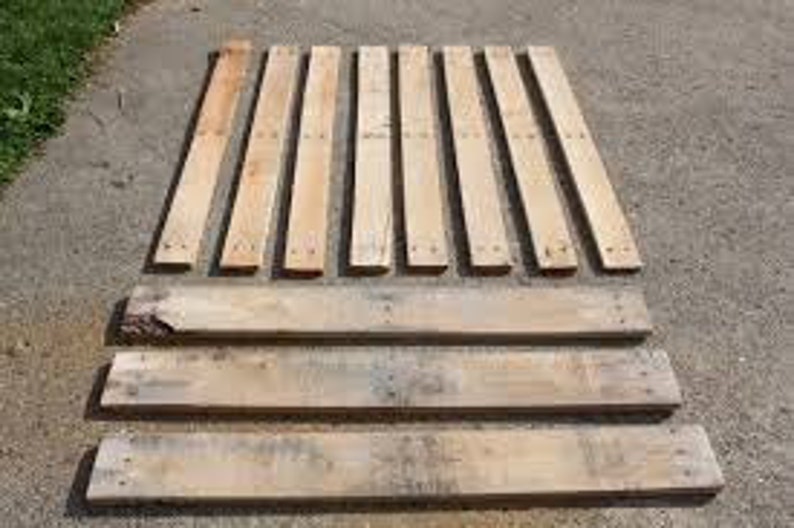 May include: Ten wooden planks, some with nail holes, arranged in two rows. The planks are all approximately the same length and width. They are a light brown color and appear to be made of reclaimed wood.