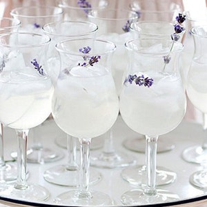 May include: A tray of clear glass goblets filled with a white liquid and garnished with lavender sprigs.