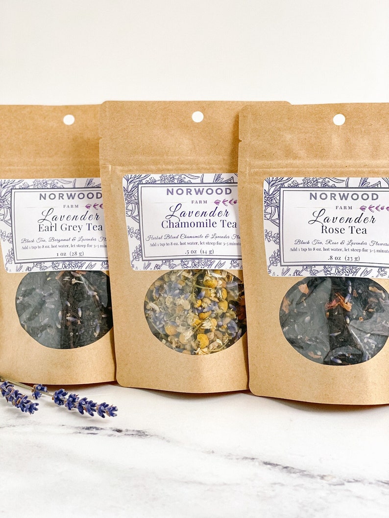 May include: Three brown paper bags with clear windows showing different types of loose leaf tea blends. The bags are labeled "Norwood Farm Lavender Earl Grey Tea", "Norwood Farm Lavender Chamomile Tea", and "Norwood Farm Lavender Rose Tea".