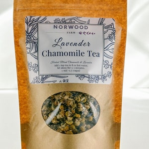 May include: A brown paper bag with a white label that reads "NORWOOD FARM Lavender Chamomile Tea". The label also includes the text "Herbal Blend Chamomile & Lavender", "Add 1 tsp tea to 8 oz hot water, let steep for 3-5 minutes", and "1 oz(-1.5 cups)". The bag has a clear window that shows the dried chamomile and lavender tea blend.