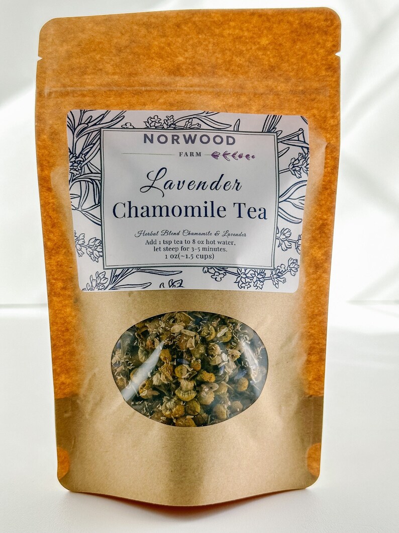 May include: A brown paper bag with a white label that reads "NORWOOD FARM Lavender Chamomile Tea". The label also includes the text "Herbal Blend Chamomile & Lavender", "Add 1 tsp tea to 8 oz hot water, let steep for 3-5 minutes", and "1 oz(-1.5 cups)". The bag has a clear window that shows the dried chamomile and lavender tea blend.