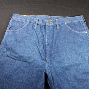 May include: A pair of blue denim jeans with a button fly and belt loops. The jeans have two front pockets and two back pockets.