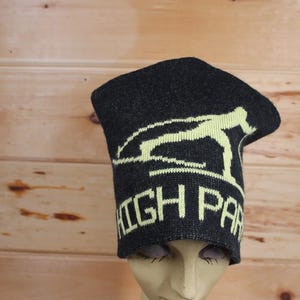 May include: Black knit beanie with a yellow graphic of a person skiing and the text "HIGH PARK" in yellow.