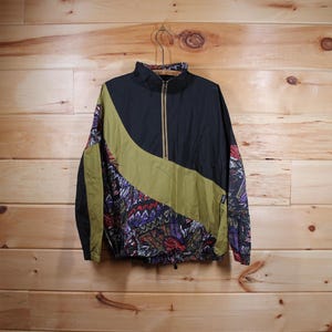 May include: A black, green and purple windbreaker jacket with a zip closure. The jacket has a geometric pattern on the sleeves and a solid black panel on the front.