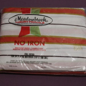 Peut inclure: Un drap-housse blanc à rayures rouges et dorées. L'emballage indique "Meadowbrook Luxury Percale" et "No Iron". Le drap est pour un matelas de taille double, 54 x 75 pouces (137 x 190 cm).
