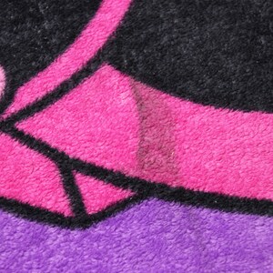 Pode incluir: Close-up de um tecido estampado em rosa e preto com textura felpuda. O tecido tem um contorno preto e um fundo rosa.