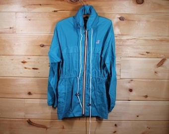 May include: A turquoise blue hooded jacket with a white zipper and white drawstrings. The jacket has a small logo on the left chest.