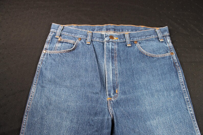 May include: A pair of blue denim jeans with a classic five-pocket style. The jeans have a straight leg and a dark wash.