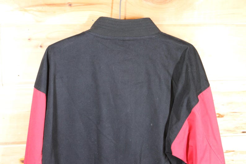 K&ouml;nnte beinhalten: Schwarz-rote Jacke mit langen &Auml;rmeln und Rei&szlig;verschluss.