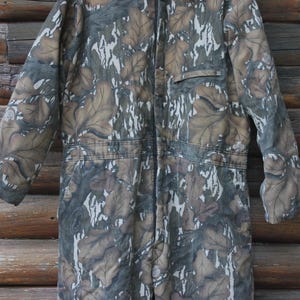 Puede incluir: Mono de camuflaje con cremallera completa, bolsillo y mangas largas. El mono presenta un dise&ntilde;o de hojas marrones, grises y blancas. La prenda est&aacute; hecha de un material duradero, adecuado para actividades al aire libre.