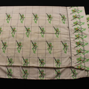 Peut inclure: Ensemble de literie blanc cassé avec un motif répété de grenouilles vertes jouant du banjo, disposées dans une grille de lignes noires. L'ensemble comprend un drap plat et des taies d'oreiller.