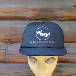 Op de afbeelding: Marineblauwe truckerpet met een wit cirkelvormig logo "Biway". Daaronder staat in rode tekst "The Best Kept Secret In Town". De pet heeft een mesh achterkant.