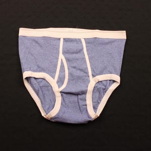 Può includere: Slip blu con fascia e finiture bianche. La biancheria intima ha un design classico con patta. Il tessuto sembra essere un materiale morbido e mélange. Lo slip è appoggiato su uno sfondo nero.