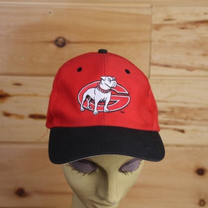 May include: Red and black baseball cap with a white bulldog logo. The logo features a bulldog with a collar and the letter "G" inside a circle.