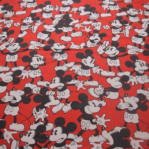 Op de afbeelding: Rode stof met een herhalend patroon van zwarte en witte Mickey Mouse-silhouetten. De Mickey Mouse-figuren staan in verschillende poses, sommige met hun handen omhoog, sommige met hun handen omlaag en sommige met hun mond open.