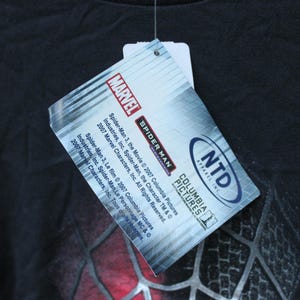 May include: A black t-shirt featuring a rectangular hang tag with the Marvel logo, Spider-Man 3 branding, and Columbia Pictures text. The tag includes copyright information for 2007 Marvel Characters, Inc. and Columbia Pictures Industries, Inc.