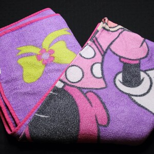 Pode incluir: Cobertor de l&atilde; polar roxo e rosa com uma imagem de desenho animado do Mickey Mouse vestindo um vestido rosa com bolinhas brancas e um la&ccedil;o amarelo. O cobertor tem uma borda rosa.