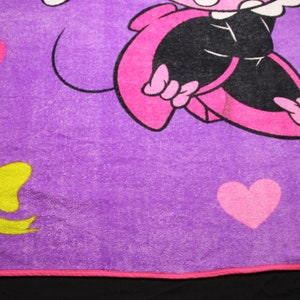Pode incluir: Cobertor de l&atilde; polar roxo com um personagem de desenho animado rosa vestindo um vestido preto e sapatos rosa. O personagem est&aacute; rodeado de cora&ccedil;&otilde;es rosas e um la&ccedil;o amarelo.