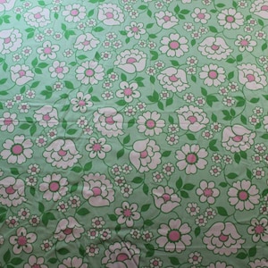 May include: A fabric featuring a floral design. White flowers with pink centres and smaller white blooms are set against a pale green backdrop. Green vines and leaves link the flowers together.