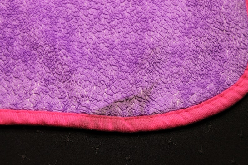 Pode incluir: Tecido felpudo roxo e rosa com uma bainha rosa. O tecido tem uma superf&iacute;cie texturizada.
