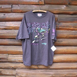 Op de afbeelding: Een donkergrijs T-shirt met een afbeelding van een persoon die skateboard. De afbeelding bevat de tekst "Asphalt" en "Rollerblade Club".