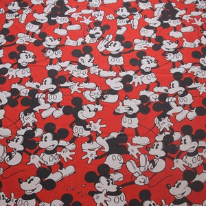 Op de afbeelding: Rode stof met een herhalend patroon van zwarte en witte Mickey Mouse figuren. De Mickey Mouse figuren staan in verschillende poses.