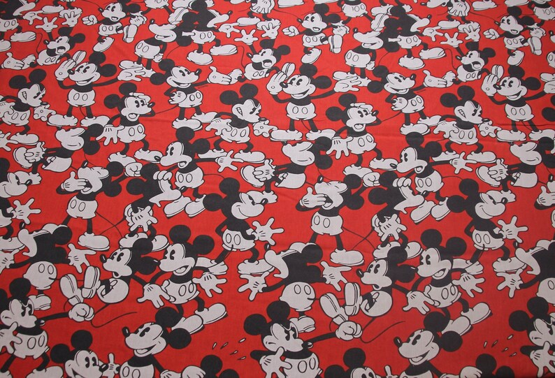 Op de afbeelding: Rode stof met een herhalend patroon van zwarte en witte Mickey Mouse figuren. De Mickey Mouse figuren staan in verschillende poses.